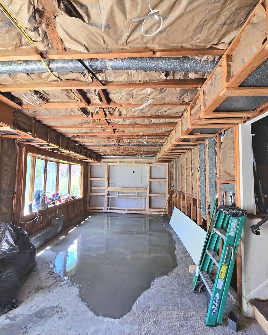 Basement stripped to the framing, with exposed ducts, insulation and fresh self-leveling concrete