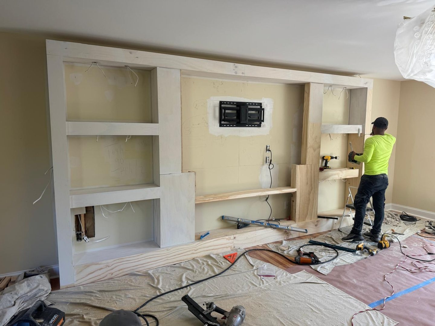 Plywood and pine framing for a full-wall built-in, with a TV mount and wiring roughed in