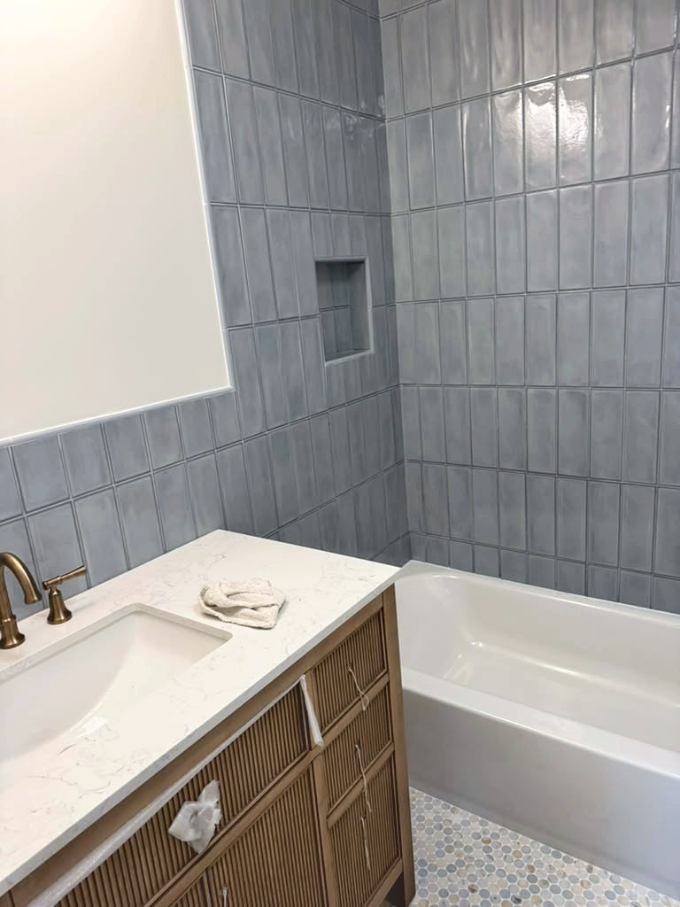 Wood vanity with brass faucet in front of blue tile
