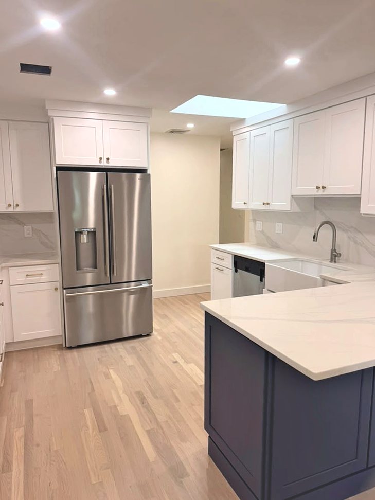 Kitchen with skylight, white cabinets and stainless refrigerator