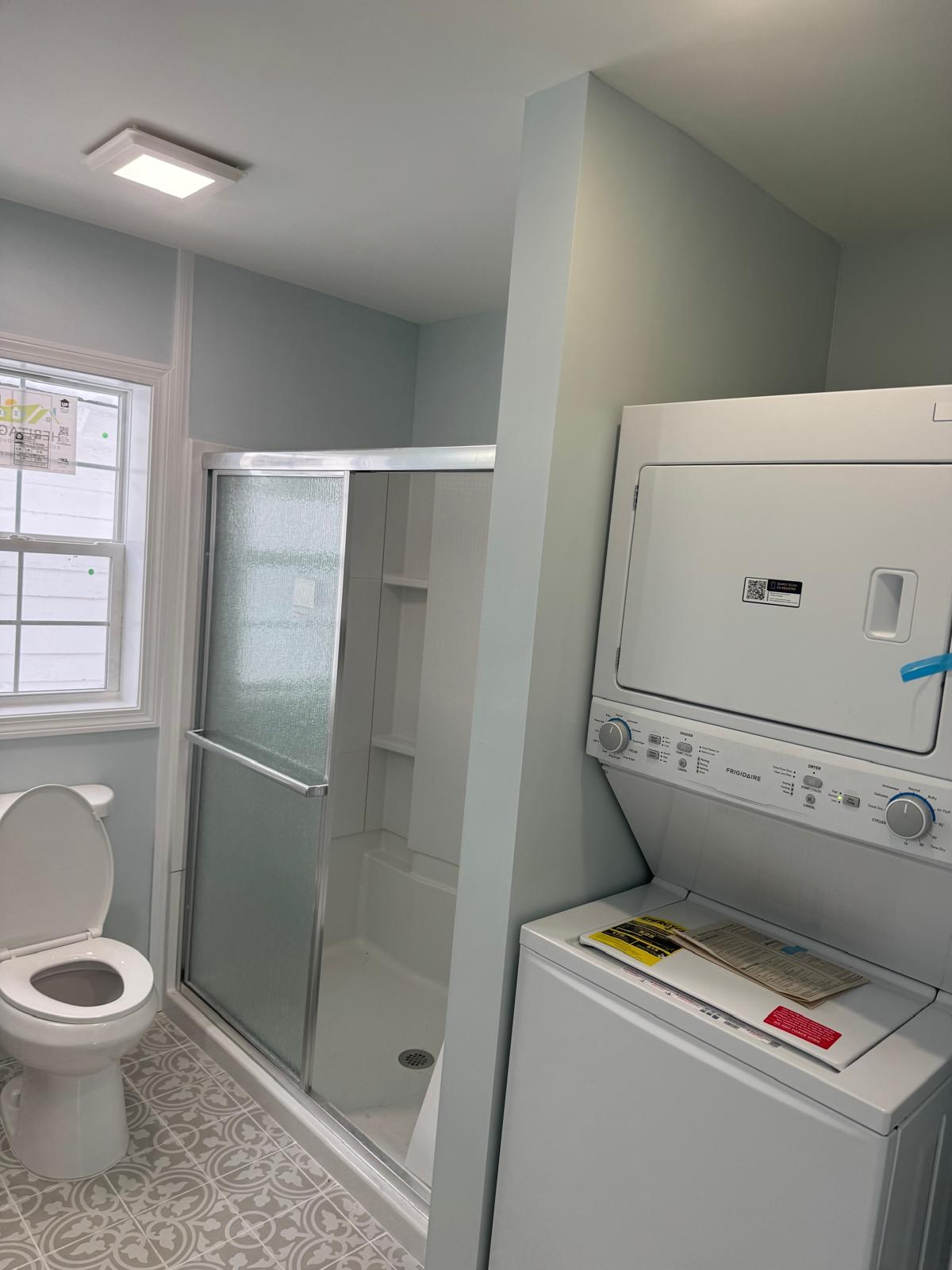 Walk-in shower next to a stacked washer and dryer