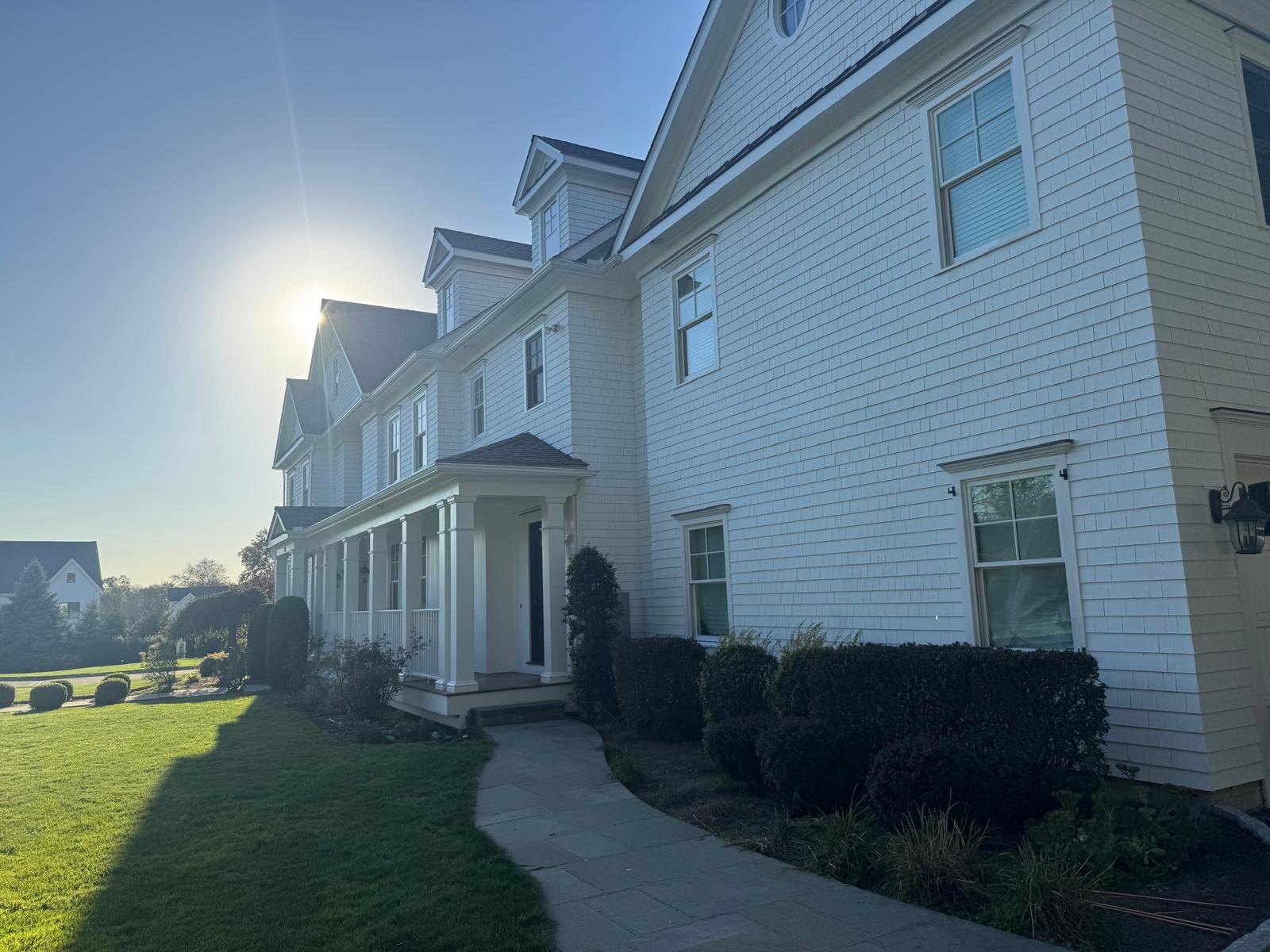 Freshly painted white shingle siding and porch in late afternoon sun