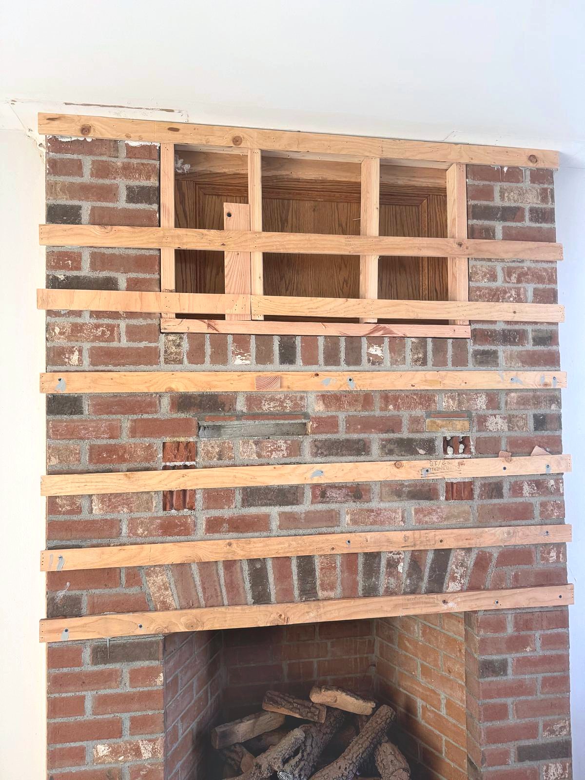 Brick fireplace with wood furring strips fastened across it, ready for framing