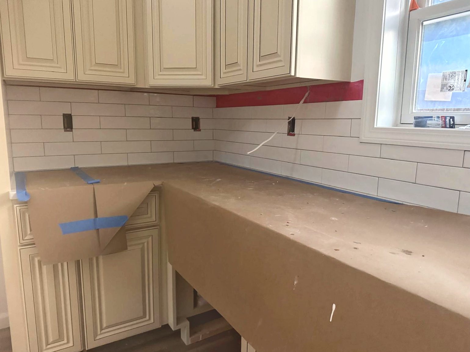 Subway tile backsplash installed above cream cabinets